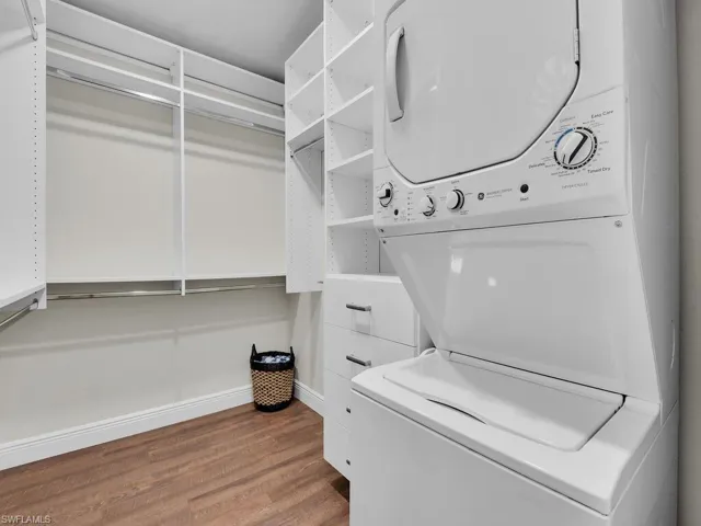 Washroom featuring stacked washer and clothes dryer and wood-type flooring