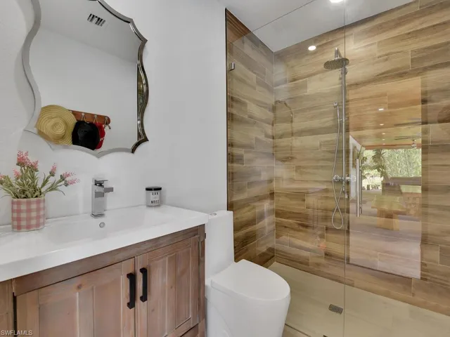 Bathroom with a shower with shower door, vanity, and toilet