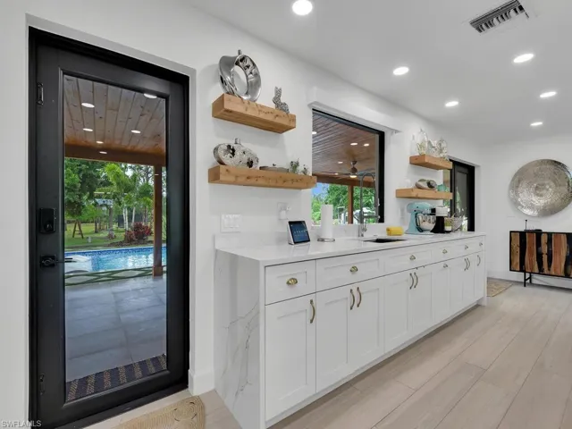 Kitchen with a wealth of natural light, white cabinets, sink, and light hardwood / wood-style flooring
