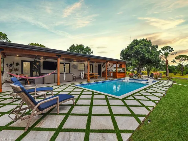 Pool at dusk featuring a patio, a lawn, and ceiling fan