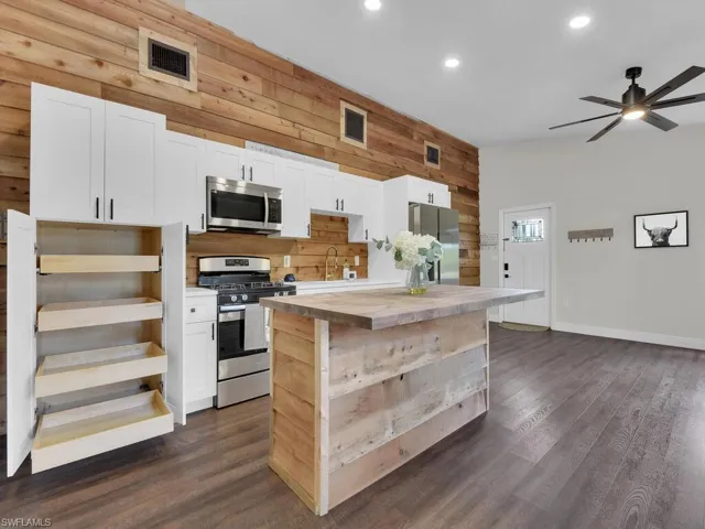 Kitchen featuring wood counters, dark hardwood / wood-style floors, a kitchen island, stainless steel appliances, and white cabinets