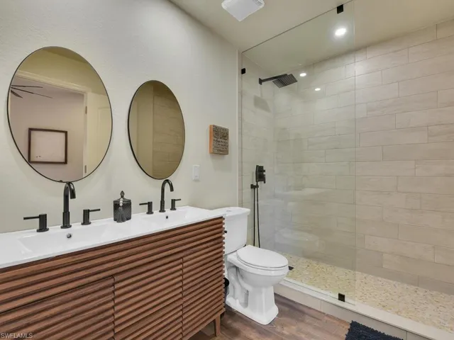 Bathroom with walk in shower, dual bowl vanity, hardwood / wood-style floors, and toilet