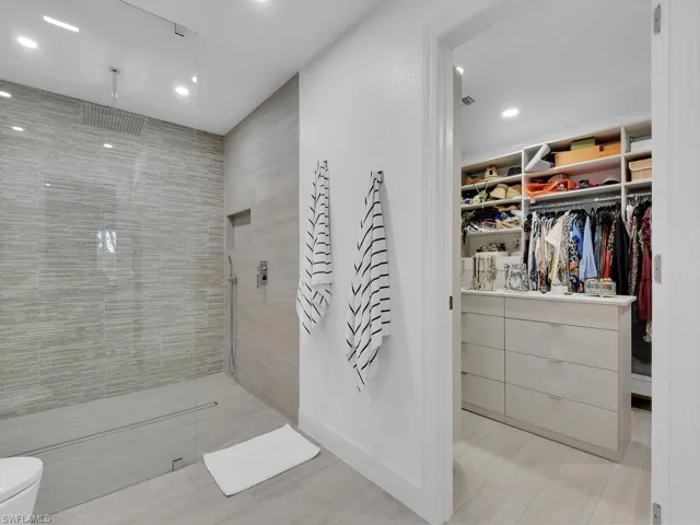 Bathroom featuring a tile shower, toilet, and tile floors