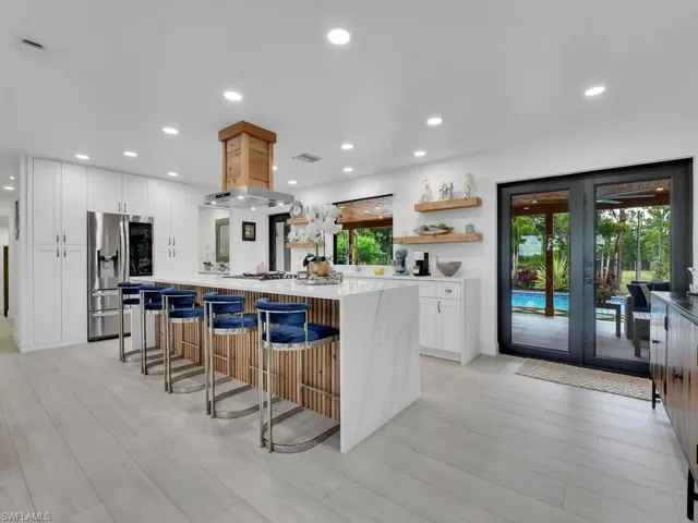 Kitchen with light wood-type flooring, white cabinetry, a breakfast bar area, and stainless steel refrigerator with ice dispenser