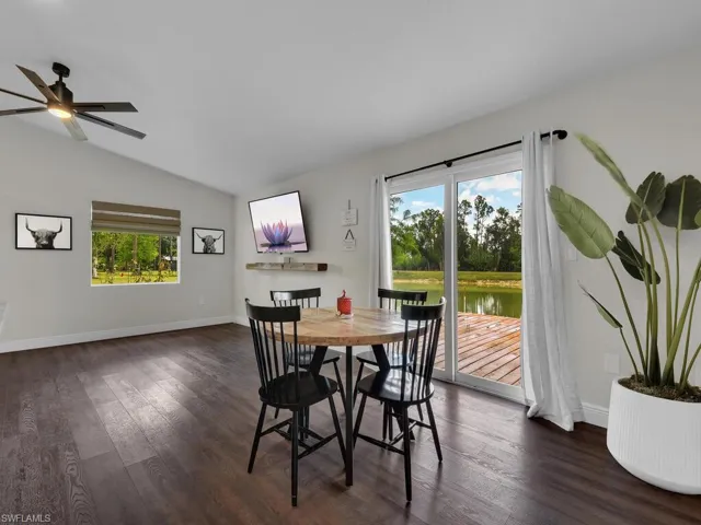 Dining room with a wealth of natural light, a water view, dark hardwood / wood-style flooring, and lofted ceiling