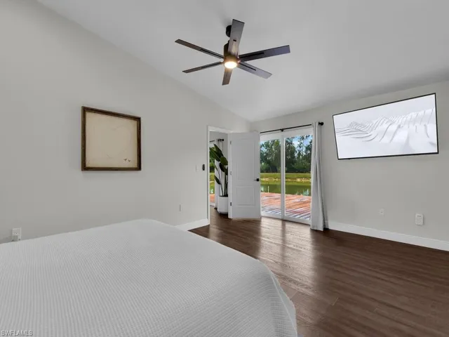 Bedroom featuring dark hardwood / wood-style flooring, ceiling fan, vaulted ceiling, and access to exterior