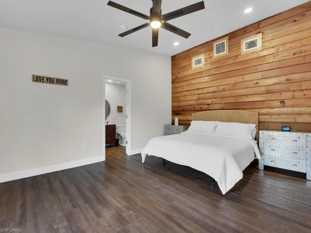 Unfurnished bedroom featuring wooden walls, ceiling fan, and dark hardwood / wood-style flooring