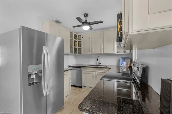 Kitchen featuring ceiling fan, granite countertops, sink, and appliances with stainless steel finishes