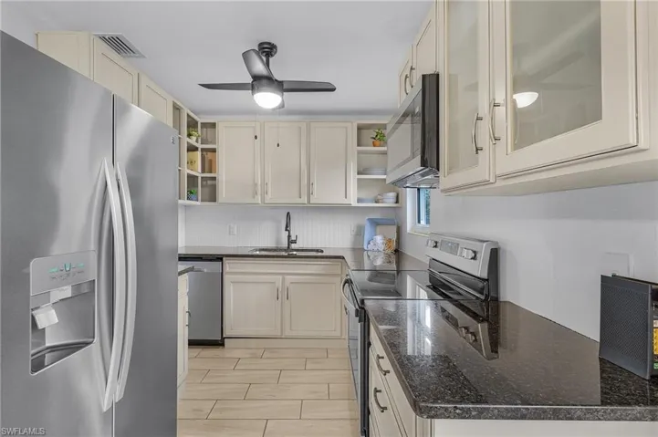 Kitchen with granite countertops, ceiling fan, sink, and appliances with stainless steel finishes