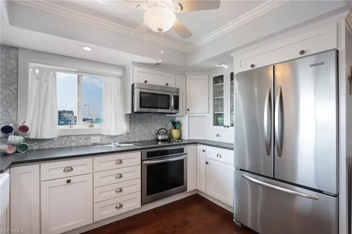 Kitchen featuring white cabinetry, stainless steel appliances, dark hardwood / wood-style floors, tasteful backsplash, and ceiling fan