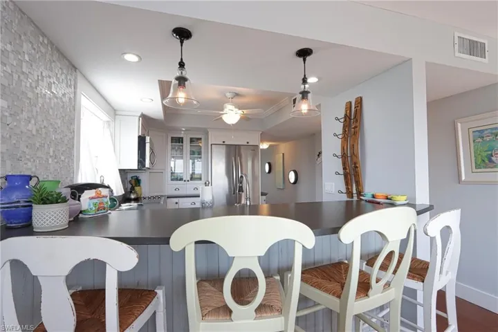 Kitchen featuring kitchen peninsula, hanging light fixtures, hardwood / wood-style floors, white cabinetry, and appliances with stainless steel finishes