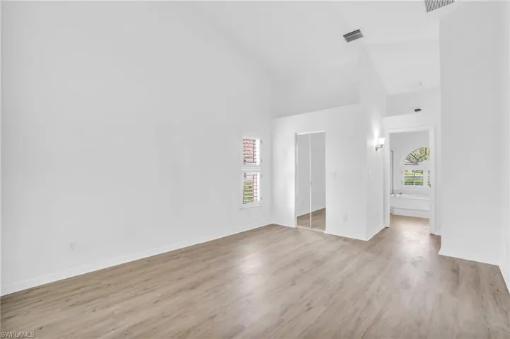 Spare room with light wood-type flooring and high vaulted ceiling