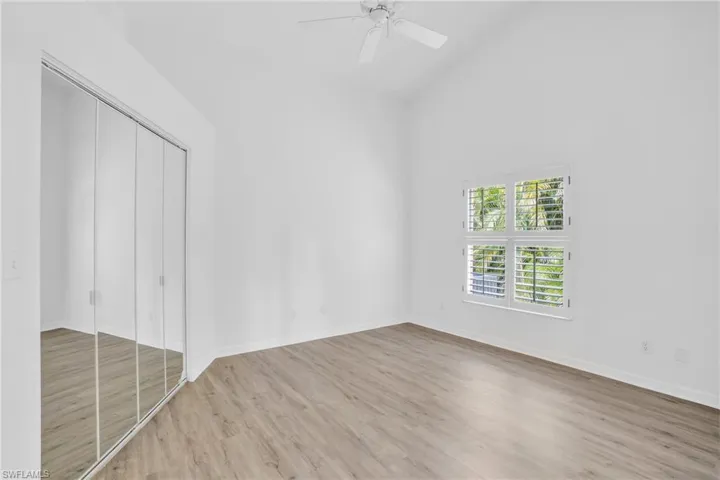 Unfurnished bedroom with light hardwood / wood-style flooring, a closet, ceiling fan, and high vaulted ceiling