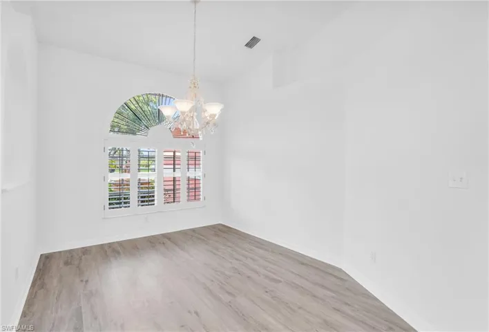 Spare room with light hardwood / wood-style flooring and a chandelier