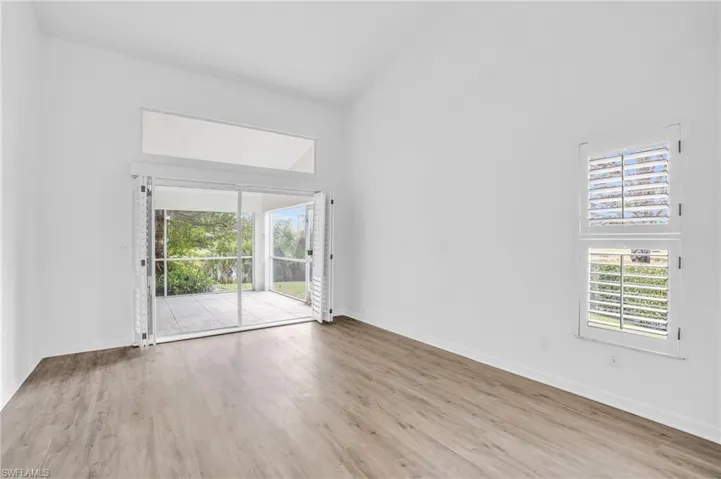 Unfurnished room with high vaulted ceiling and light wood-type flooring