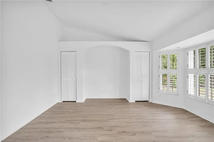 Spare room with light wood-type flooring and lofted ceiling