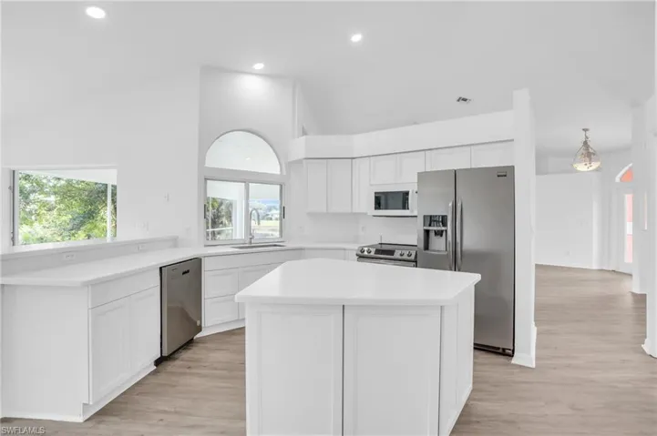 Kitchen with a center island, light hardwood / wood-style flooring, stainless steel appliances, and white cabinets