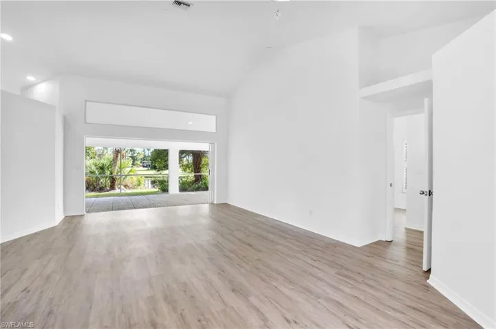 Unfurnished living room with light hardwood / wood-style floors and high vaulted ceiling