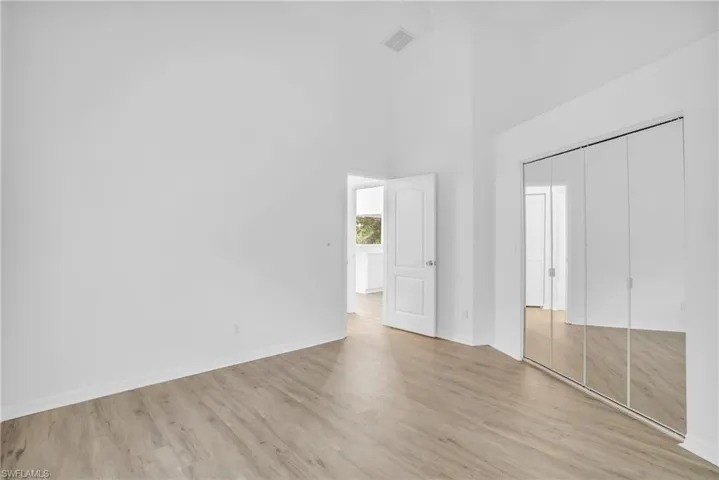 Unfurnished bedroom featuring light hardwood / wood-style flooring, a towering ceiling, and a closet