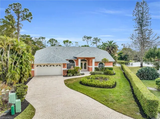 Ranch-style home with a garage, a front lawn, and a water view