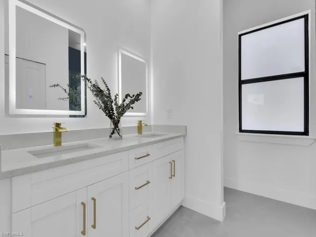 Bathroom with double vanity, a sink, and baseboards
