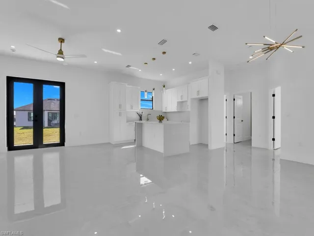 Unfurnished living room featuring recessed lighting, visible vents, baseboards, and ceiling fan with notable chandelier