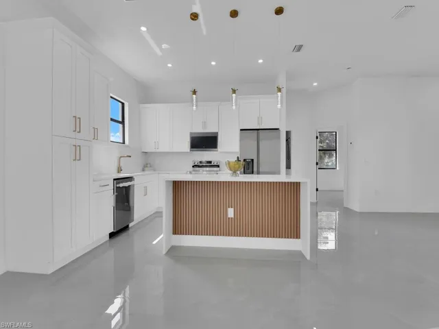 Kitchen featuring light countertops, appliances with stainless steel finishes, white cabinetry, recessed lighting, and a kitchen island