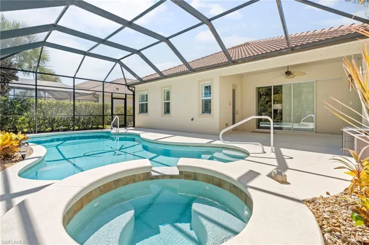 View of pool with a sunroom, a patio, a pool with connected hot tub, glass enclosure, and ceiling fan
