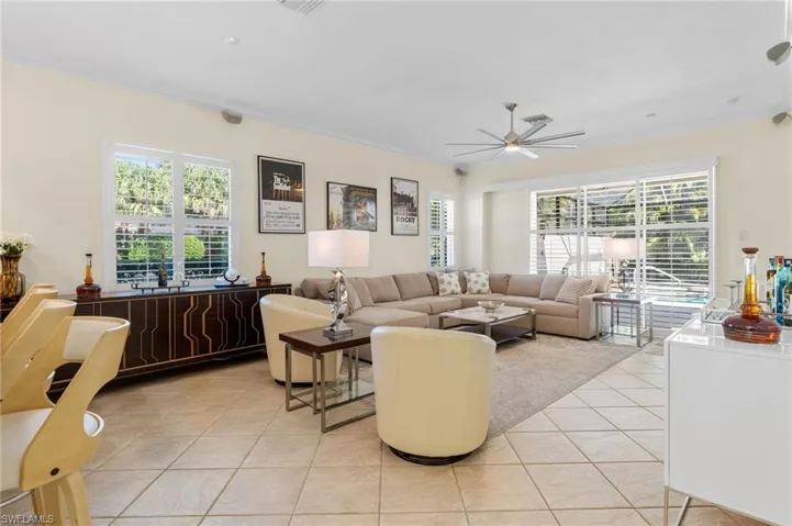 Living room with light tile patterned flooring, plenty of natural light, crown molding, and a ceiling fan