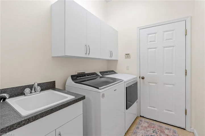 Laundry area with separate washer and dryer, cabinet space, and light tile patterned floors