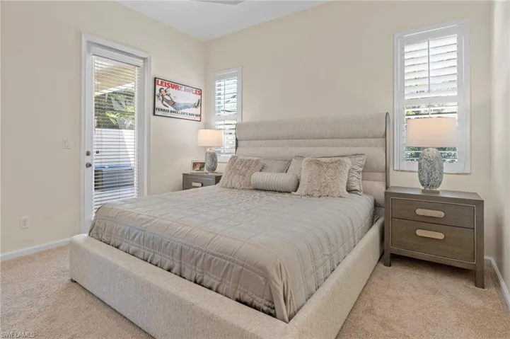 Bedroom with light colored carpet, multiple windows, and access to exterior