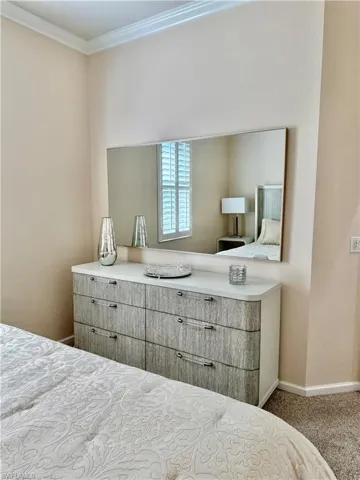 Carpeted bedroom with ornamental molding and a textured wall