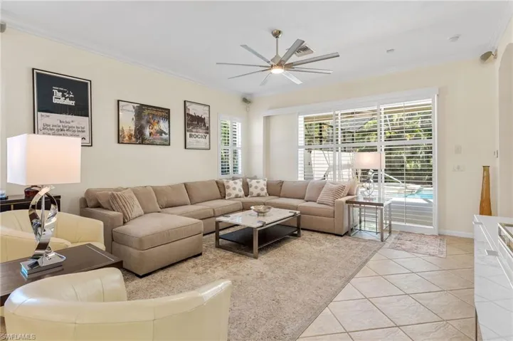 Living area with crown molding, light tile patterned floors, and ceiling fan