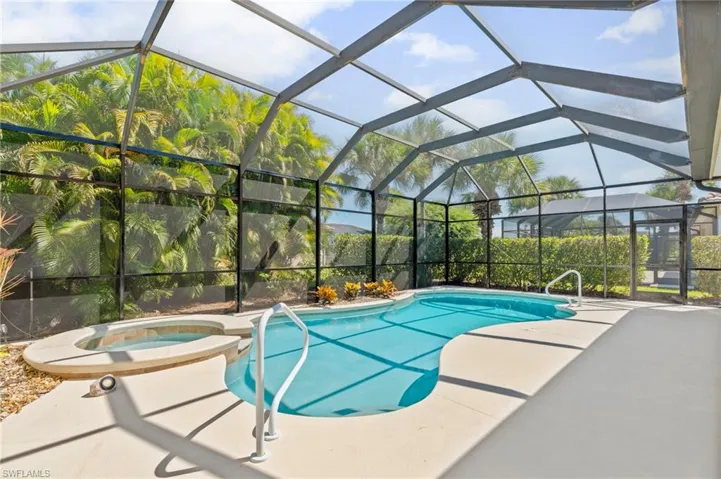 View of swimming pool featuring glass enclosure, a pool with connected hot tub, a sunroom, and a patio area