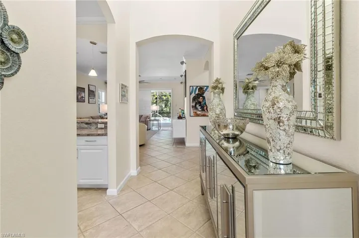 Hallway featuring arched walkways, light tile patterned flooring, and crown molding