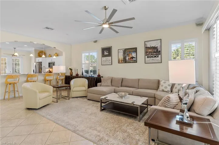 Living room with ornamental molding, healthy amount of natural light, light tile patterned flooring, and ceiling fan