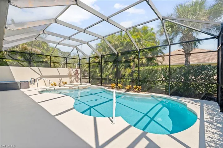 View of swimming pool featuring glass enclosure, a sunroom, a pool with connected hot tub, and a patio