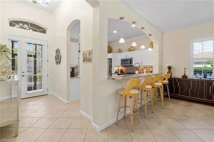 Kitchen with plenty of natural light, decorative light fixtures, tasteful backsplash, light tile patterned floors, and crown molding