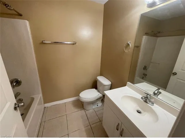 Full bath with tile patterned floors, vanity, bathtub / shower combination, baseboards, and toilet