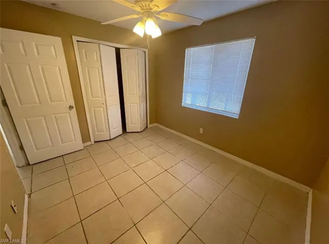 Unfurnished bedroom with a closet, a ceiling fan, baseboards, and light tile patterned floors
