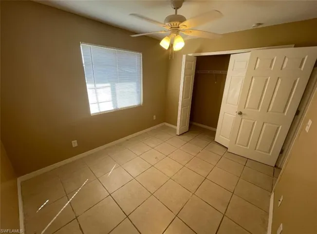 Unfurnished bedroom with a ceiling fan, baseboards, a closet, and light tile patterned floors