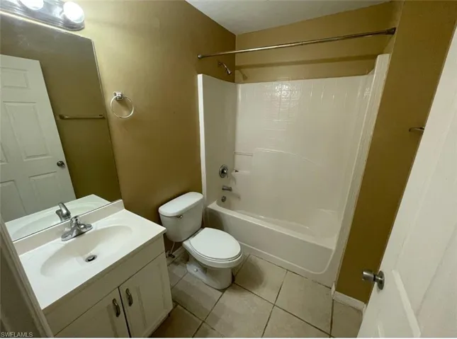 Full bathroom with tile patterned flooring, shower / washtub combination, toilet, vanity, and baseboards