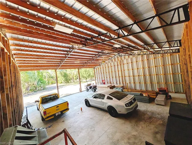 Spacious structure featuring a concrete floor, exposed wood beam ceiling, metal roof, and corrugated metal wall