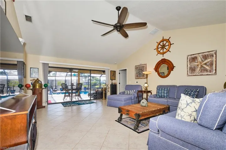 Living room with visible vents, high vaulted ceiling, light tile patterned floors, and a ceiling fan