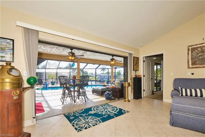 Living area featuring ceiling fan, lofted ceiling, a sunroom, and tile patterned flooring