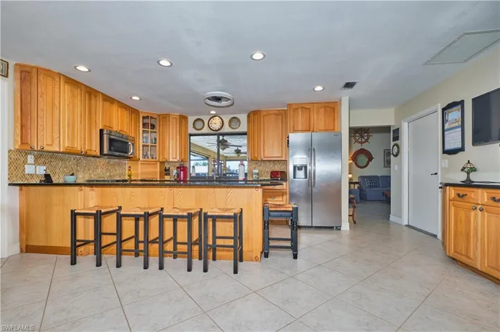 Kitchen featuring a kitchen bar, visible vents, dark countertops, and appliances with stainless steel finishes