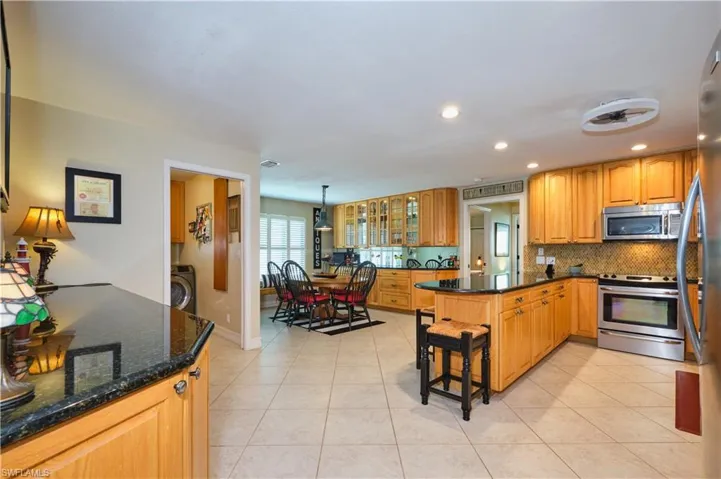 Kitchen with decorative backsplash, light tile patterned flooring, washer / dryer, and appliances with stainless steel finishes
