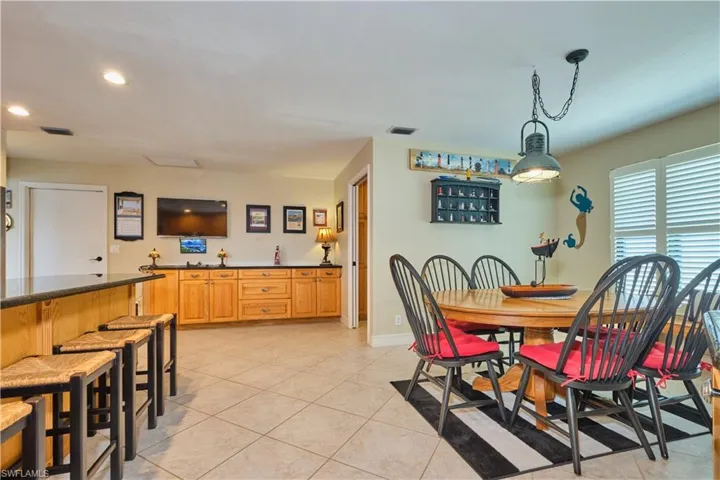 Dining room with light tile patterned flooring, recessed lighting, bar, and visible vents