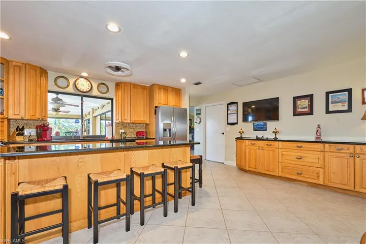 Kitchen featuring a kitchen breakfast bar, light tile patterned floors, stainless steel fridge, and tasteful backsplash