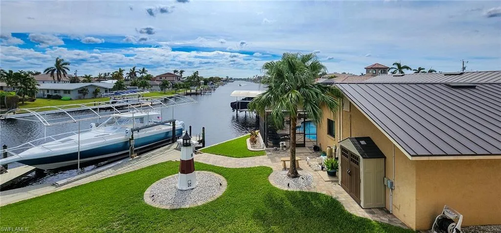 Dock area featuring boat lift, a water view, a patio area, and a lawn